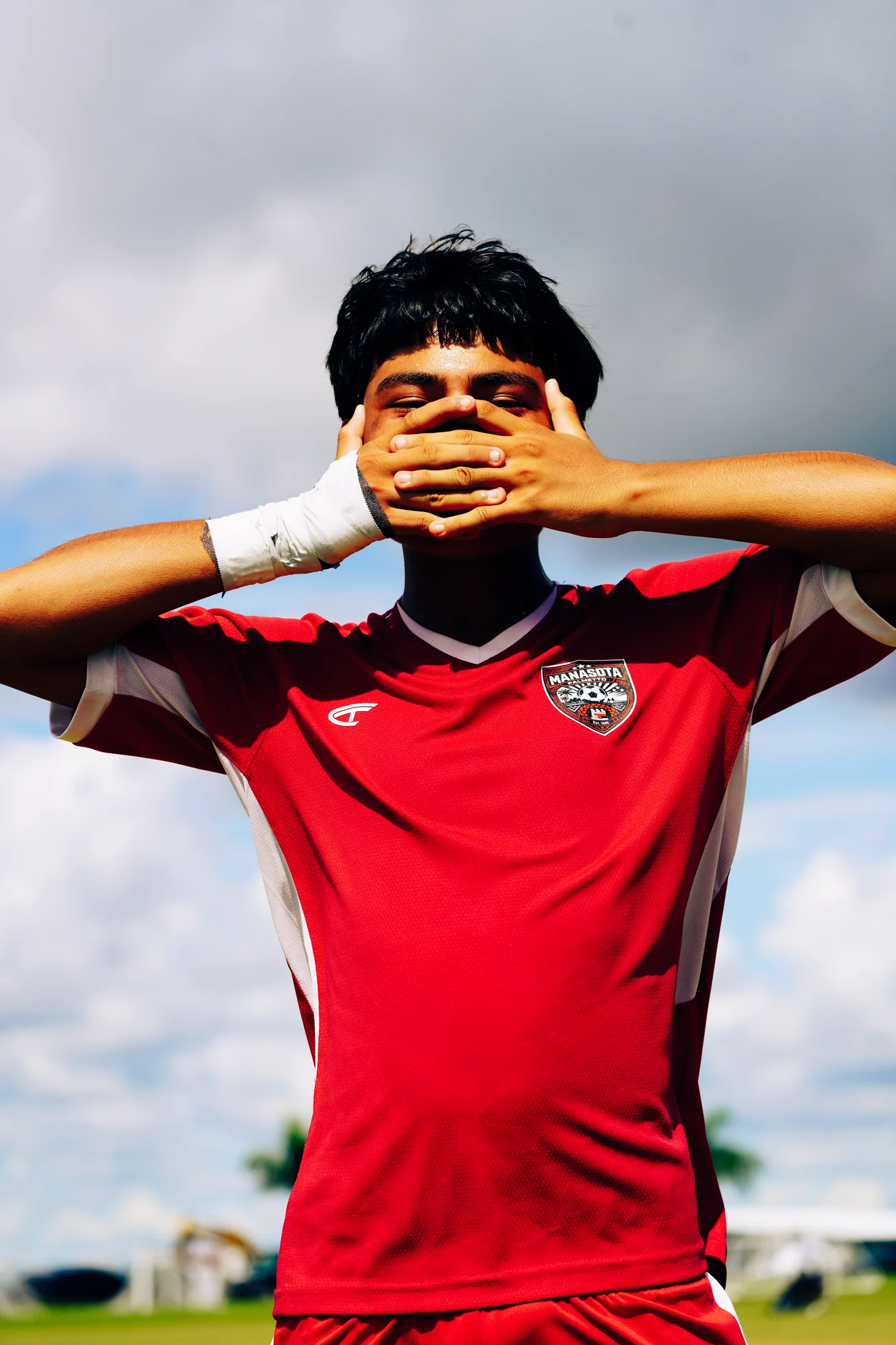 Soccer player in a red uniform framed against the sky