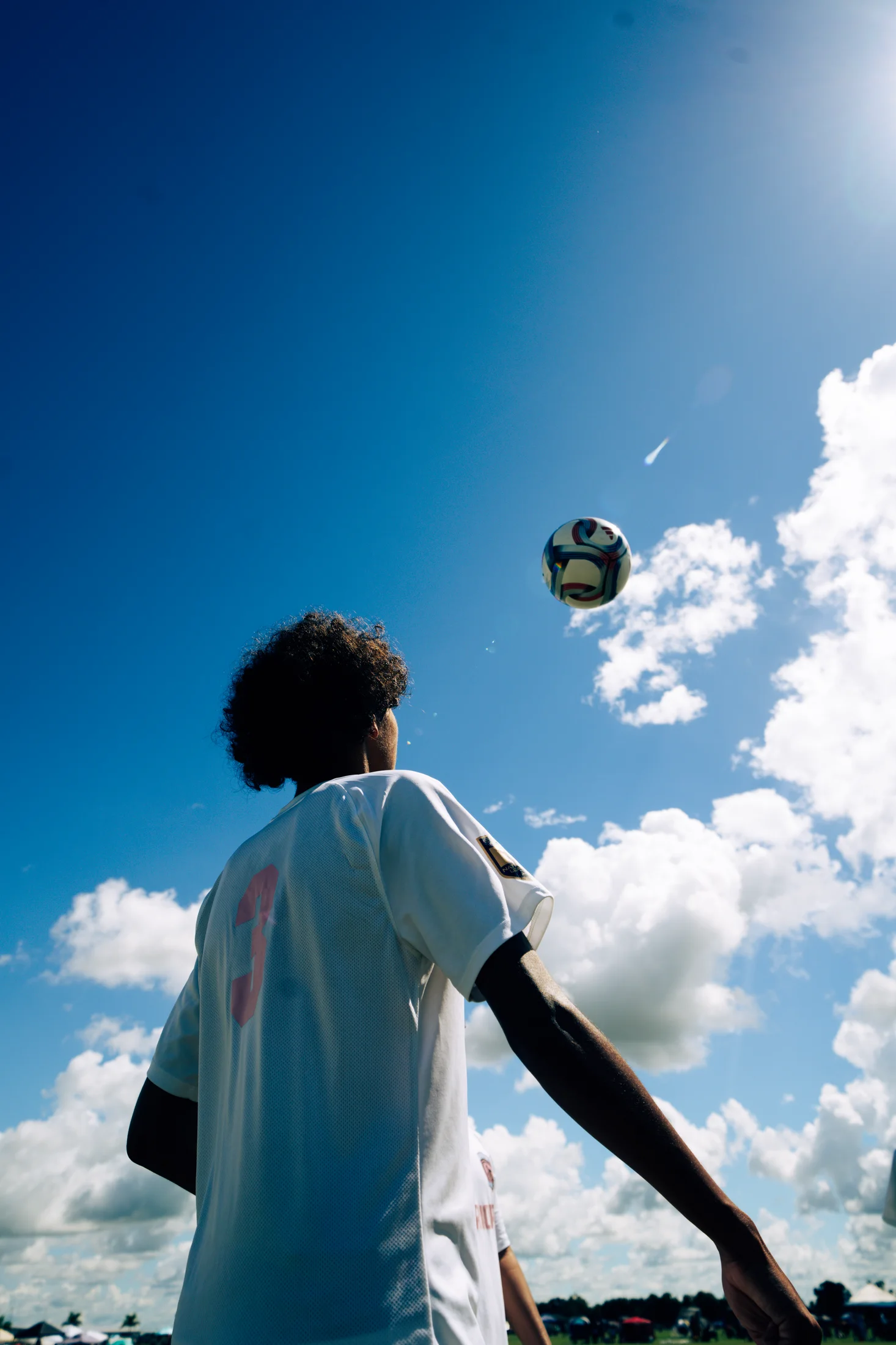 Soccer player tracking a ball against a dramatic Florida sky